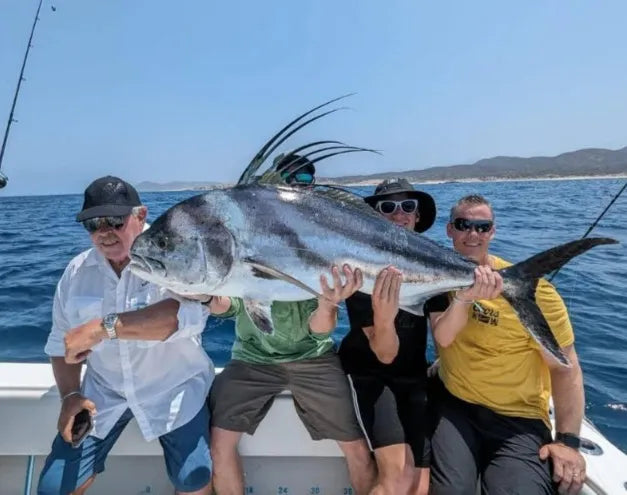 A group of individuals on a boat, proudly displaying a large fish they have caught during their outing.