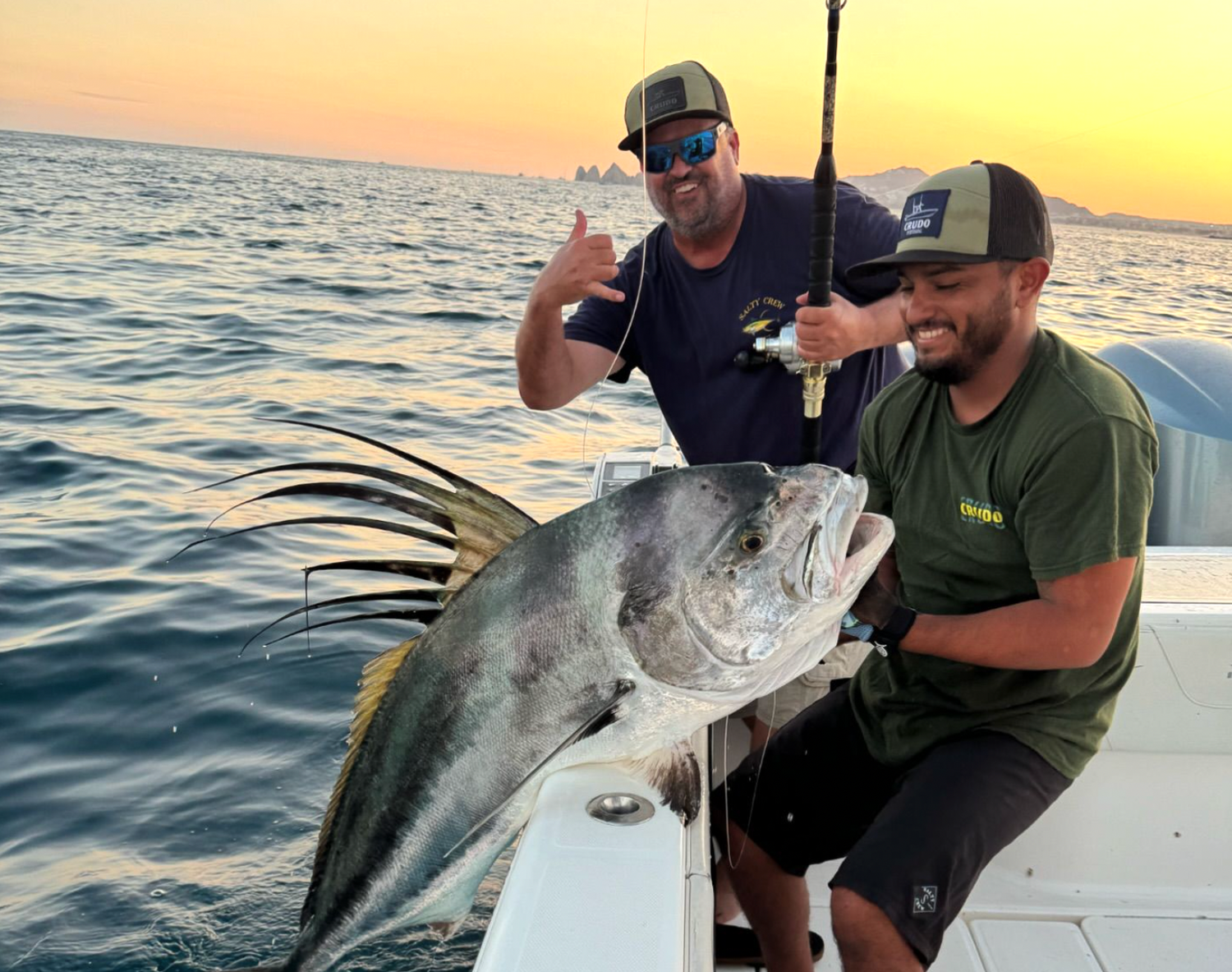 Two men proudly display a large fish they have caught, showcasing their successful fishing expedition.